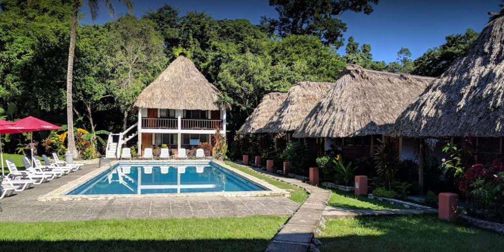 蒂卡尔Hotel Tikal Inn的一座带游泳池的度假村,位于一座建筑旁边