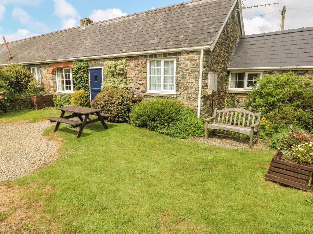 RochEynons Cottage的院子里设有野餐桌和长凳的房子