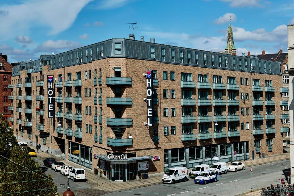哥本哈根卡宾城市酒店的一座大型砖砌建筑,停车场内有车辆停放