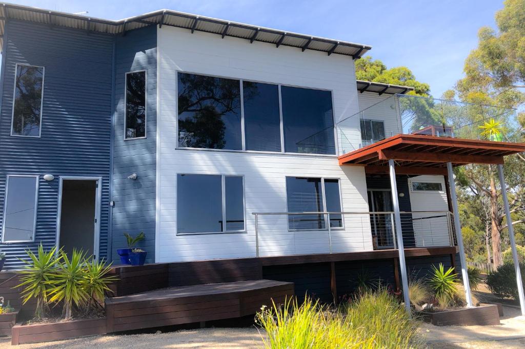 比那隆湾BAY OF FIRES BEACH SHACK ocean views from a modern Beachhouse的蓝色和白色的房子,设有门廊