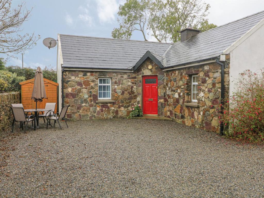 RamsgrangeRose Cottage的石头小屋设有红色的门和桌椅
