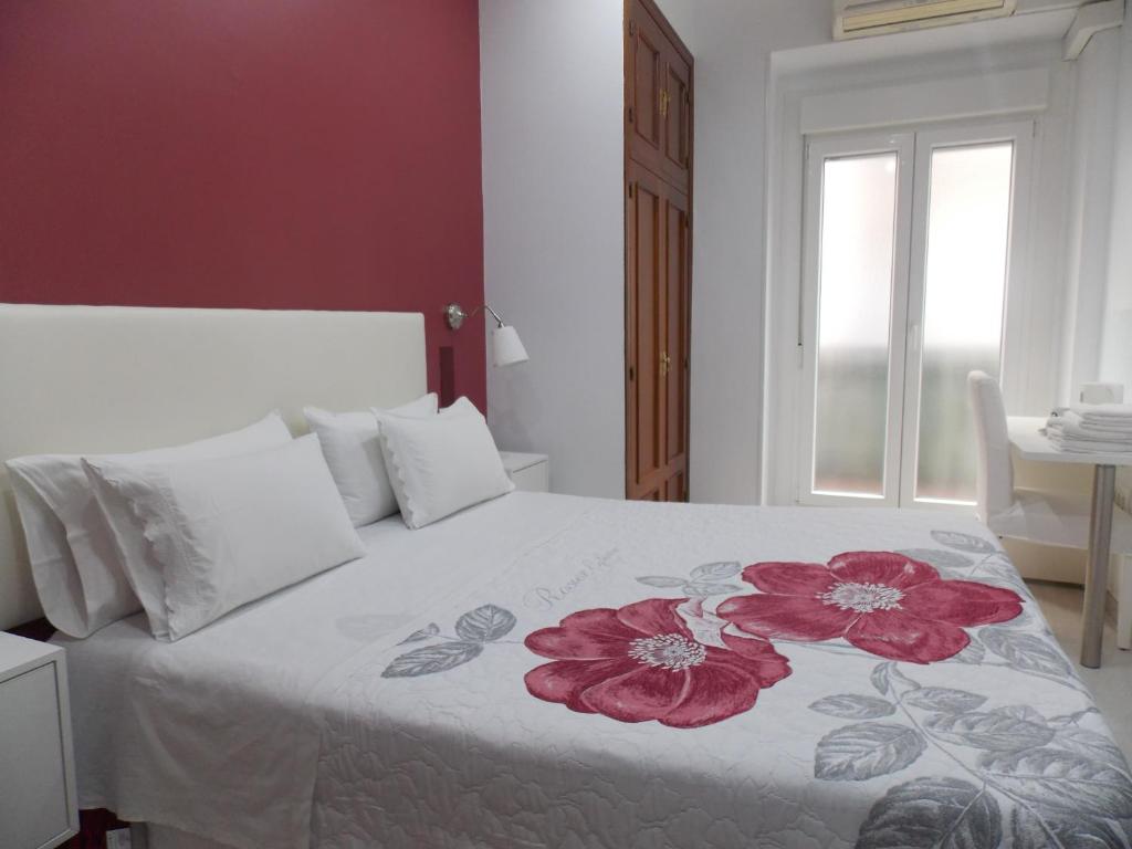 马德里Pensión Corbero的一间卧室,床上有红色的鲜花