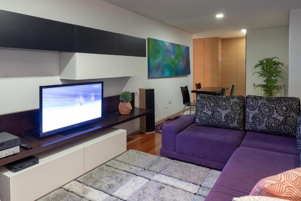 波尔图Porto Dragão的客厅配有紫色沙发和电视