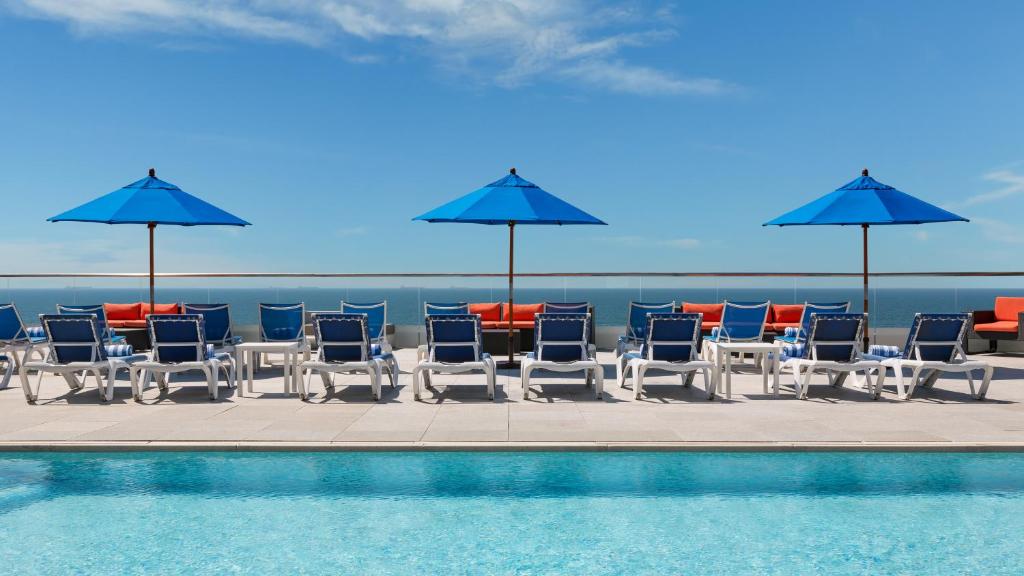 长滩阿乐格利亚酒店的一组椅子和遮阳伞,位于游泳池旁