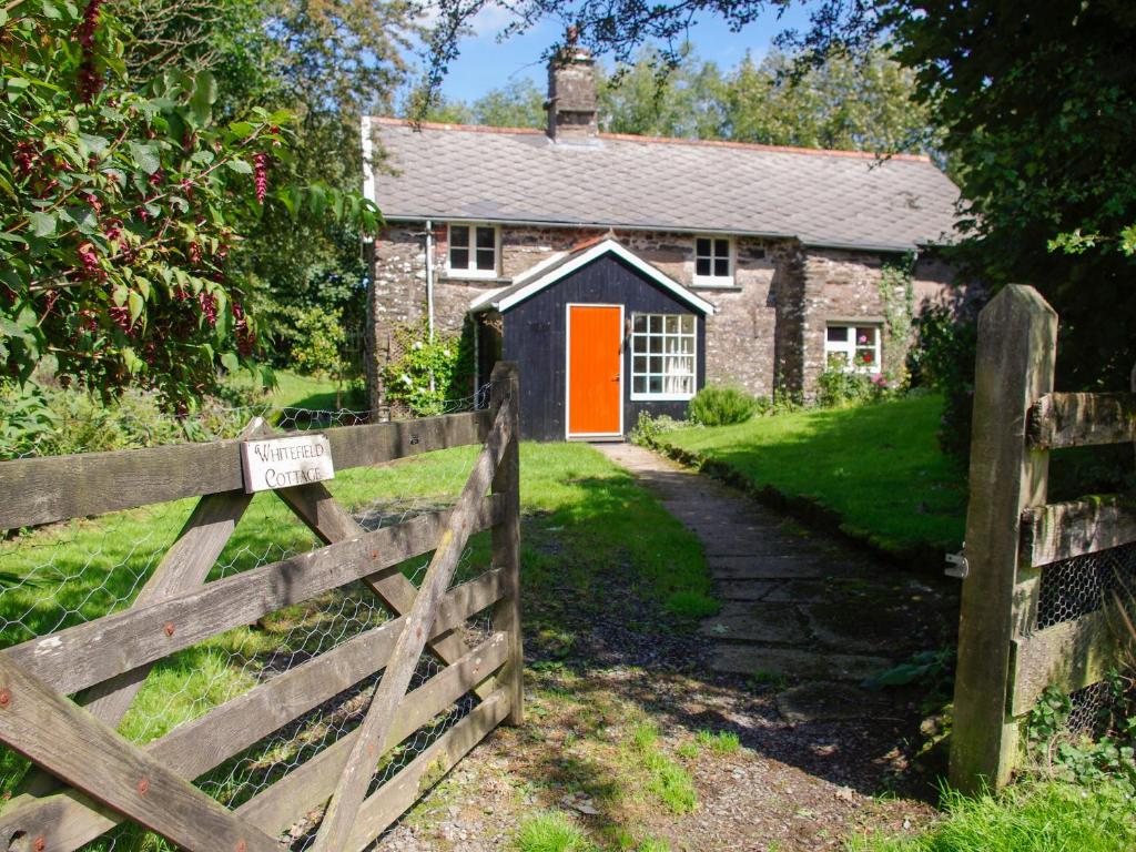 巴恩斯特珀尔Whitefield Cottage的一座带橙色门和围栏的农舍