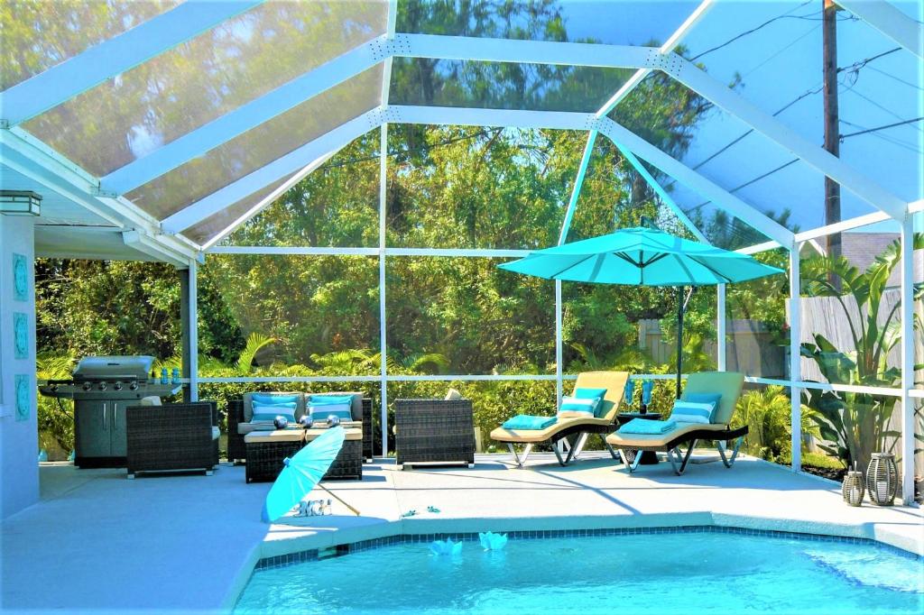 威尼斯Contemporary Cozy Pool Villa II - Pool & Nearby Beach的游泳池旁的天井配有椅子和遮阳伞。