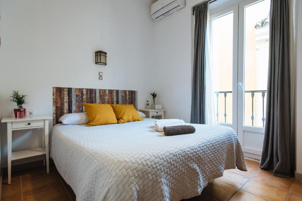 塞维利亚塞维利亚韦尔耶罗旅馆的一间卧室配有一张带黄色枕头的床和一扇窗户