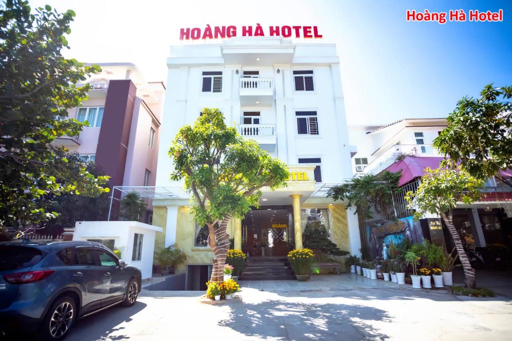 绥和市Hoàng Hà Hotel的停在大楼前的汽车