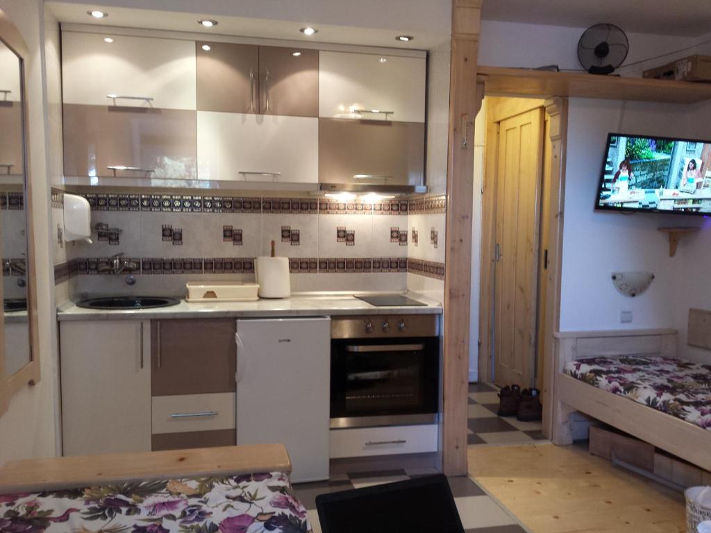 科帕奥尼克apartman na stazi的一间厨房,配有白色橱柜和一台电视机