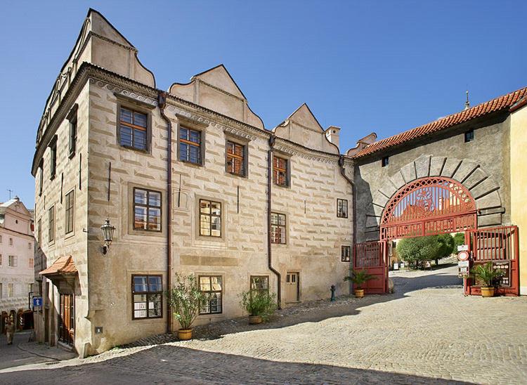 捷克克鲁姆洛夫赞美卡膳食旅馆 - 城堡公寓的一座大型石头建筑,设有大型拱门