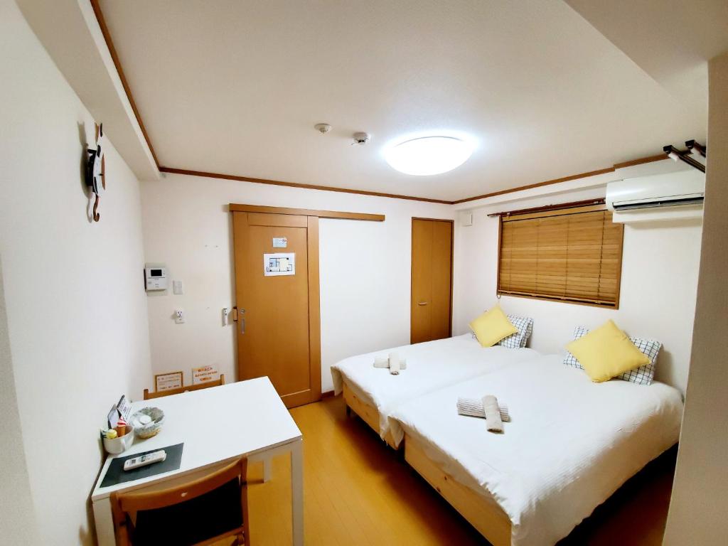 神户Takaraboshi room 201 Sannomiya 10 min的酒店客房配有两张床和一张书桌