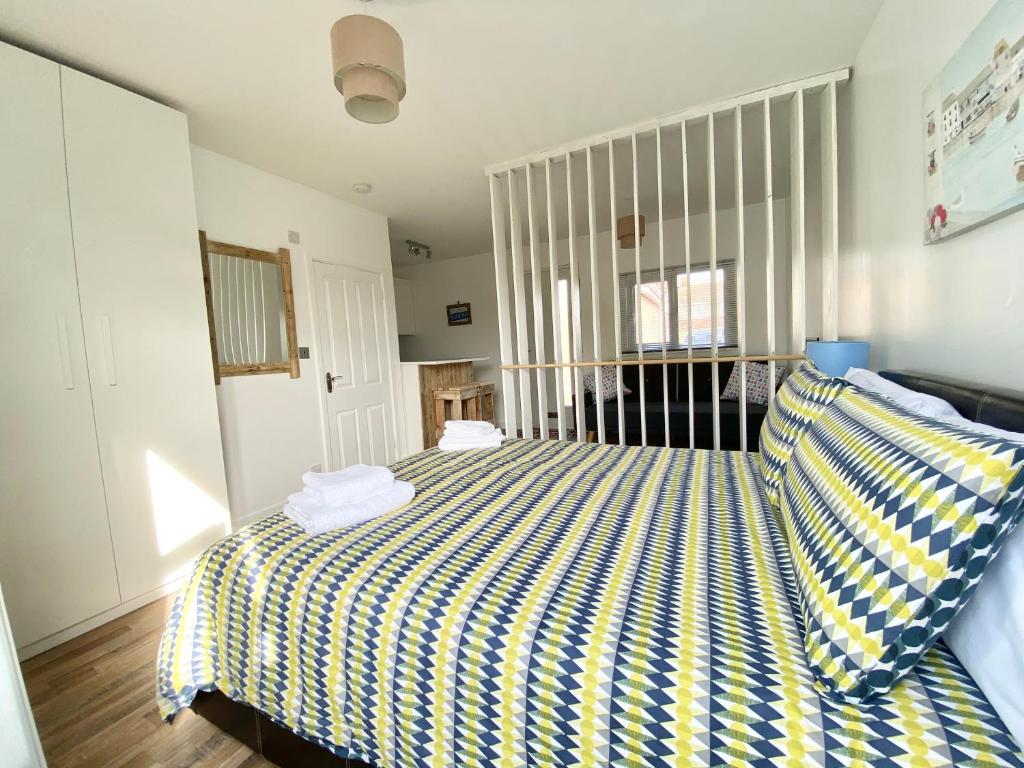 马盖特Margate Seaside Retreat的一间卧室配有一张带黄色和蓝色条纹床单的床