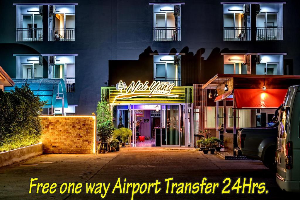 奈扬海滩Naiyang Place - Phuket Airport的前面有 ⁇ 虹灯标志的建筑
