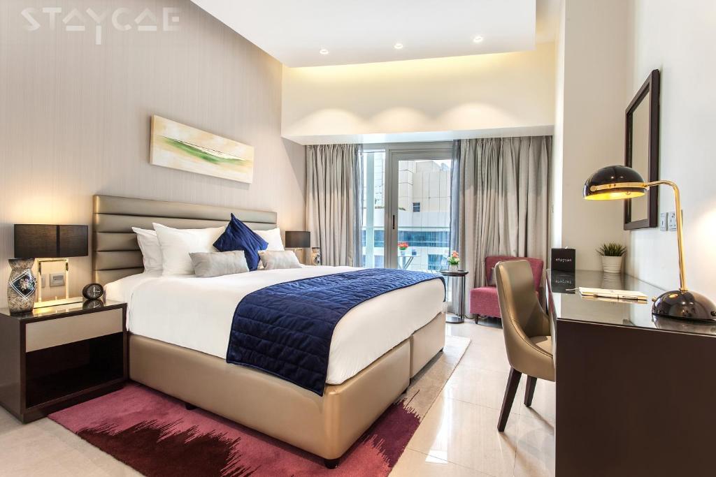 迪拜Staycae Holiday Homes - Majestine的酒店客房配有一张床、一张书桌和一张书桌。