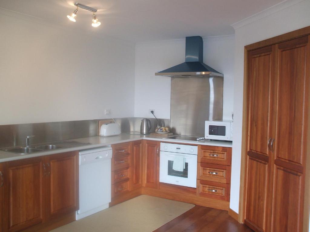 圣海伦斯St Helens On The Bay的厨房配有木制橱柜和白色炉灶烤箱。