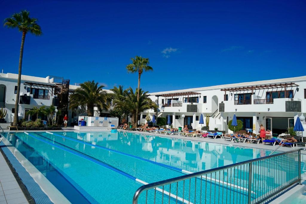 卡门港蓝色广场酒店的一座棕榈树和建筑的大型游泳池