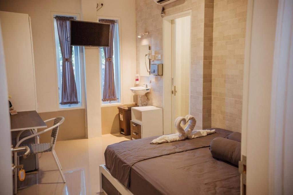 登巴萨Simple Kuta Bedroom的一间卧室配有一张床、一张桌子和一个水槽