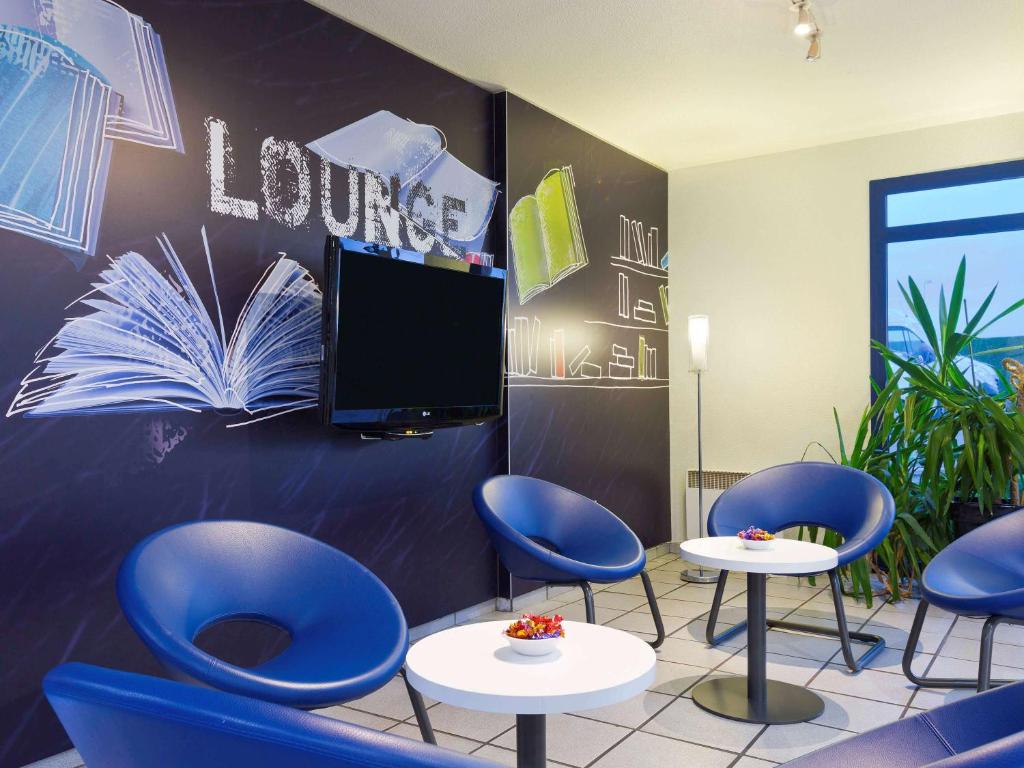 希利马扎兰ibis budget Chilly-Mazarin Les Champarts的一间设有蓝色椅子和平面电视的等候室