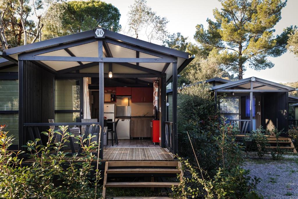 迪亚诺马里纳Oasi Camping的黑色棚屋设有木制甲板和厨房