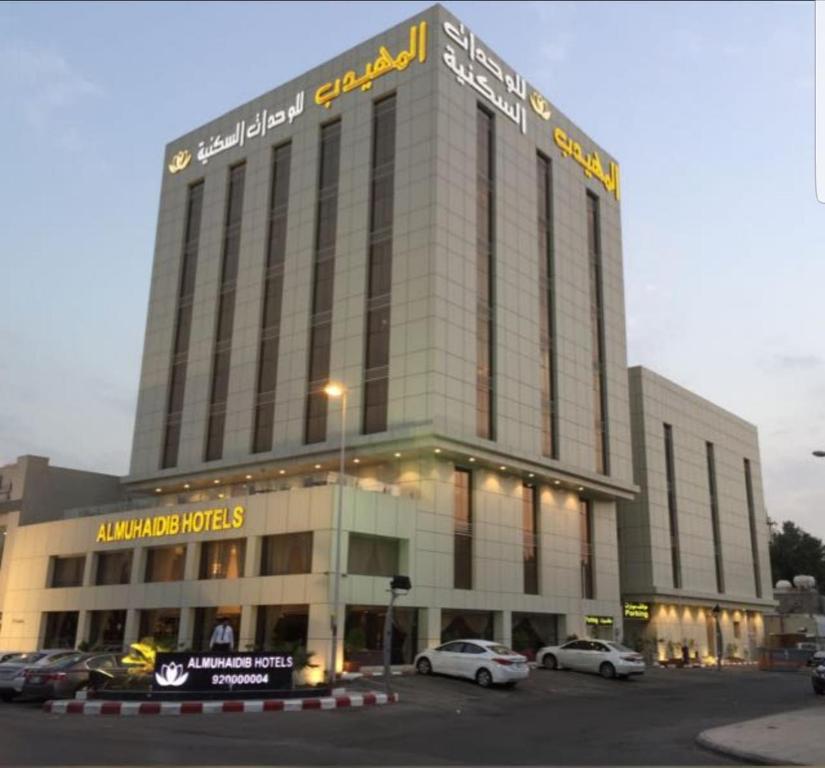 利雅德Al Muhaidb Gharnata - Al Malaz的一座大型建筑,前面有汽车停放