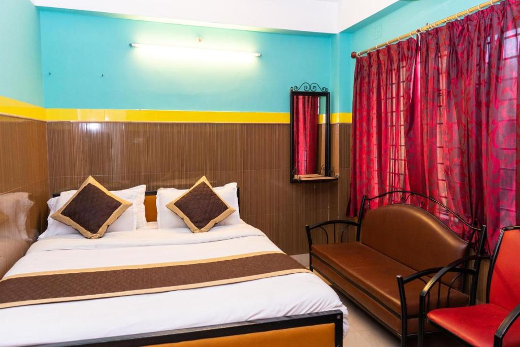 西里古里Tirupati Lodge NJP的配有一张床和一把椅子的酒店客房