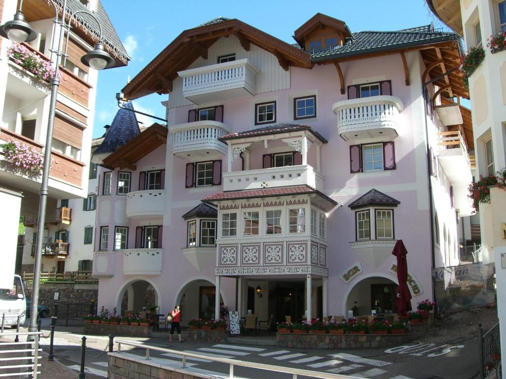 莫埃纳Ciasa Mancin Suite-Apartments的粉红色的建筑,在街上设有阳台