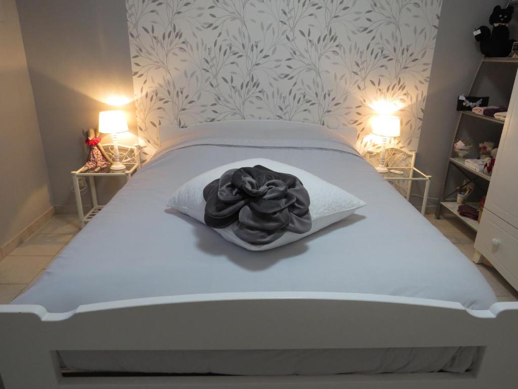 ManthelonChambre d'hôtes La Clé du Bonheur的卧室配有一张带黑色毛巾的白色床