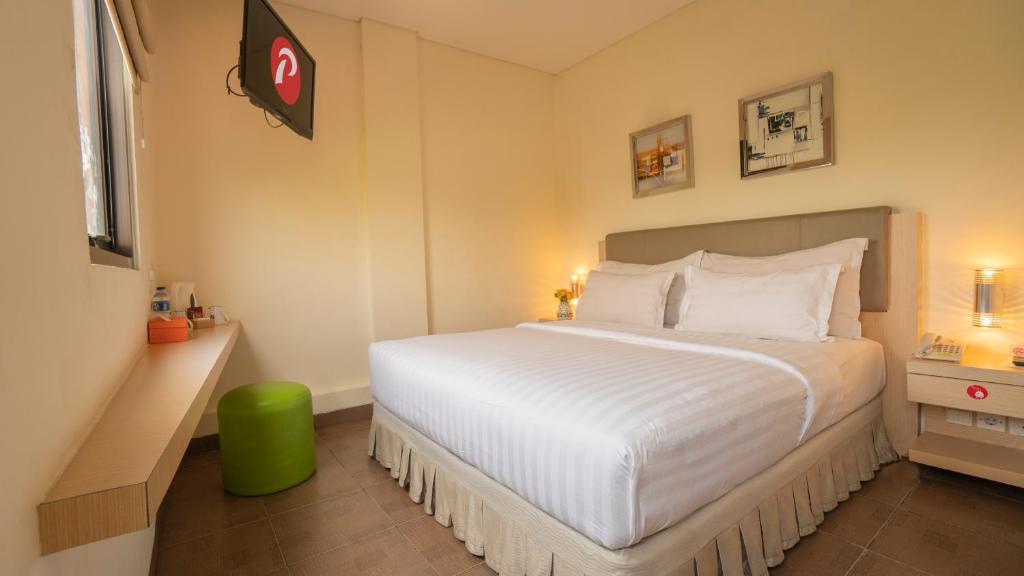 当格浪d'primahotel Airport 1的一间卧室配有一张带绿色凳子的白色大床