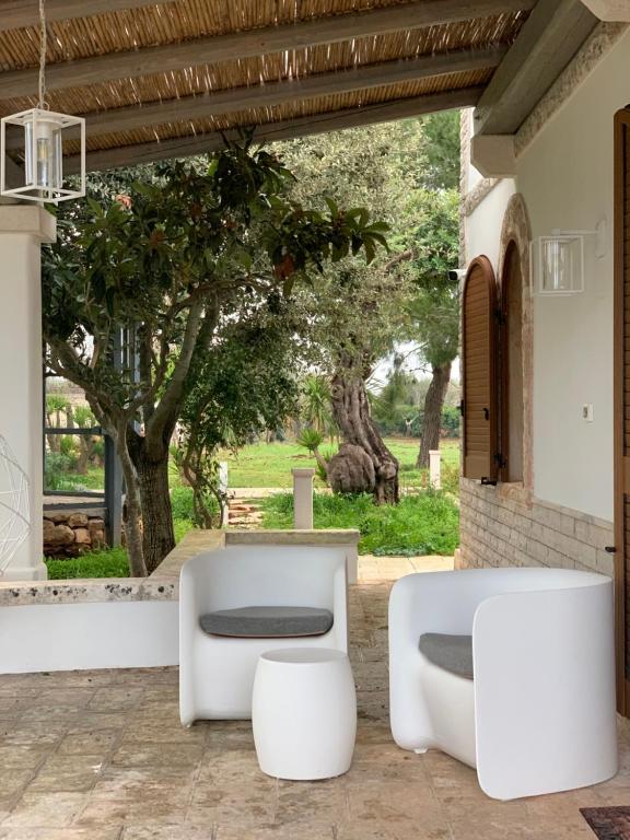普蒂尼亚诺Trullo Labellavita的庭院配有两把白色椅子和一张桌子