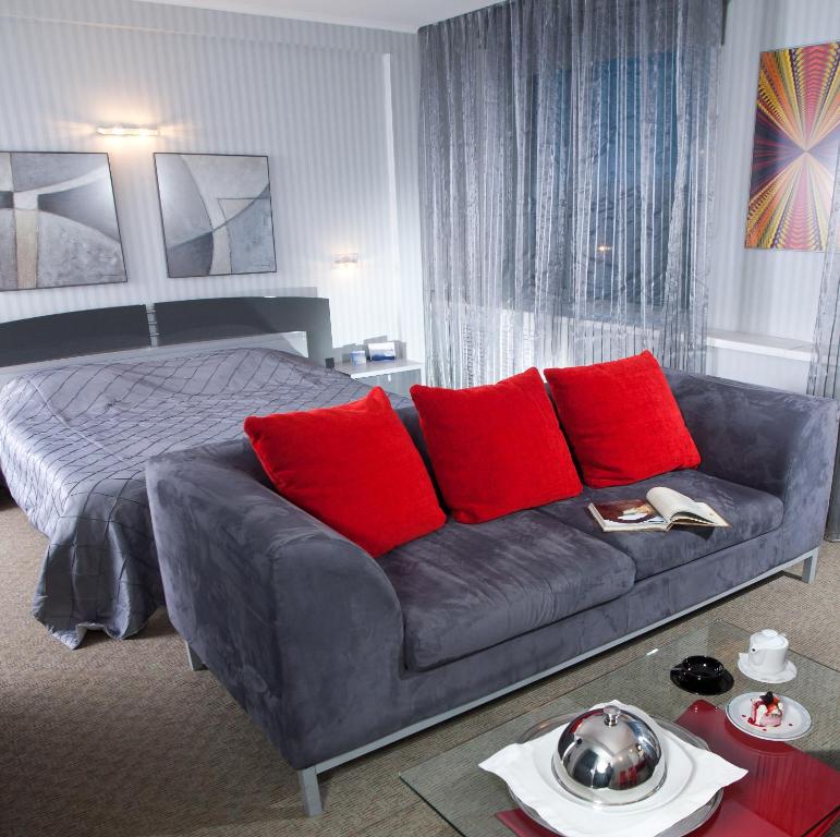 顿河畔罗斯托夫唐广场国会酒店 的一间卧室配有沙发和一张带红色枕头的床