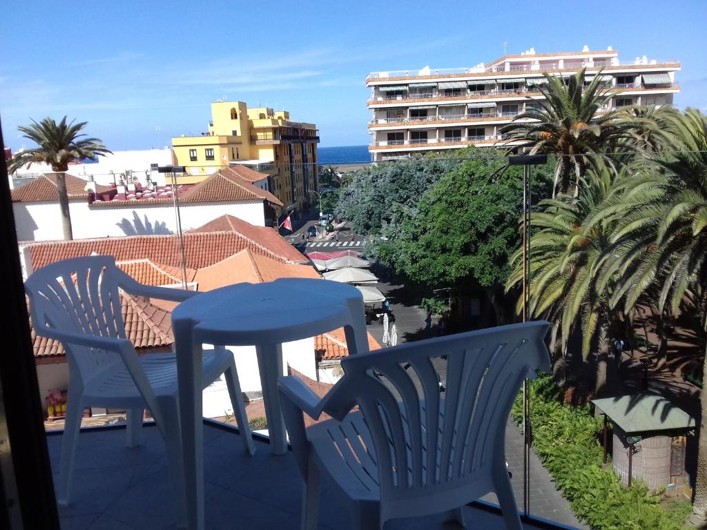 拉克鲁斯热带酒店的阳台配有两把椅子和一张桌子,公寓大楼