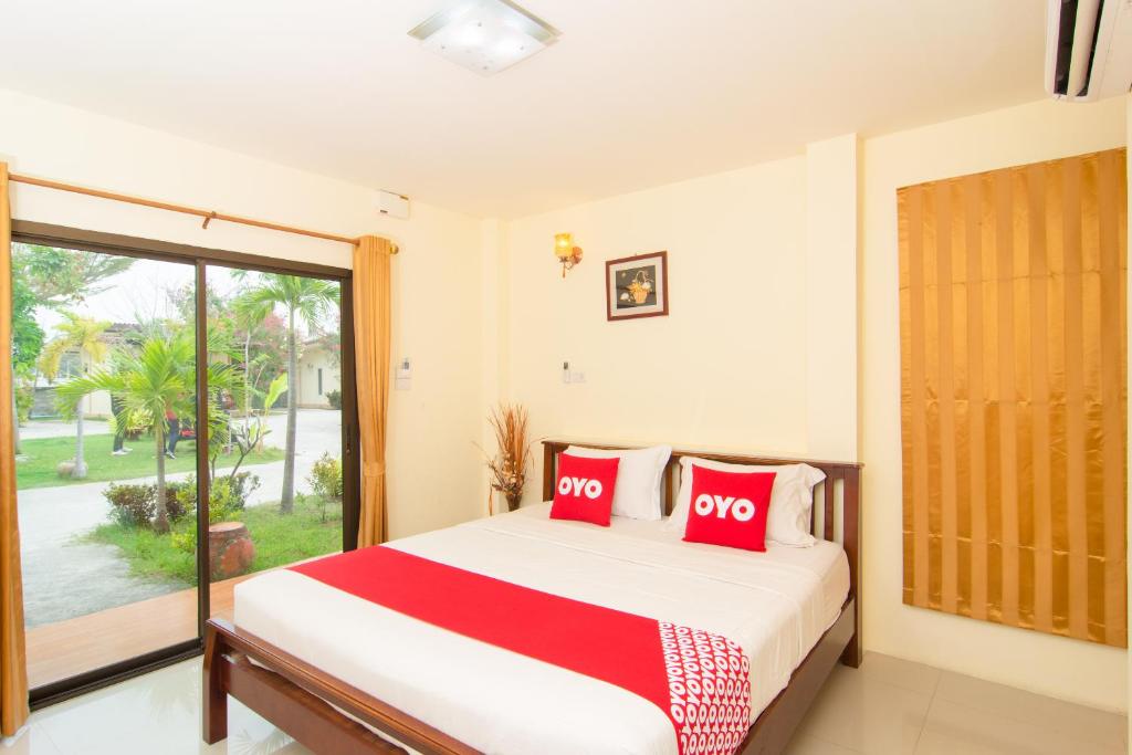 华欣OYO 607 Nawang Resort的一间卧室配有一张带红色枕头的床和一扇窗户