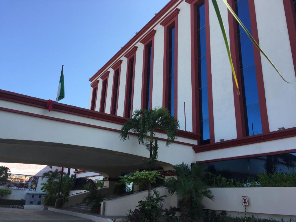 比亚埃尔莫萨Hotel Maya Tabasco的一座拥有红色和白色窗户和棕榈树的建筑