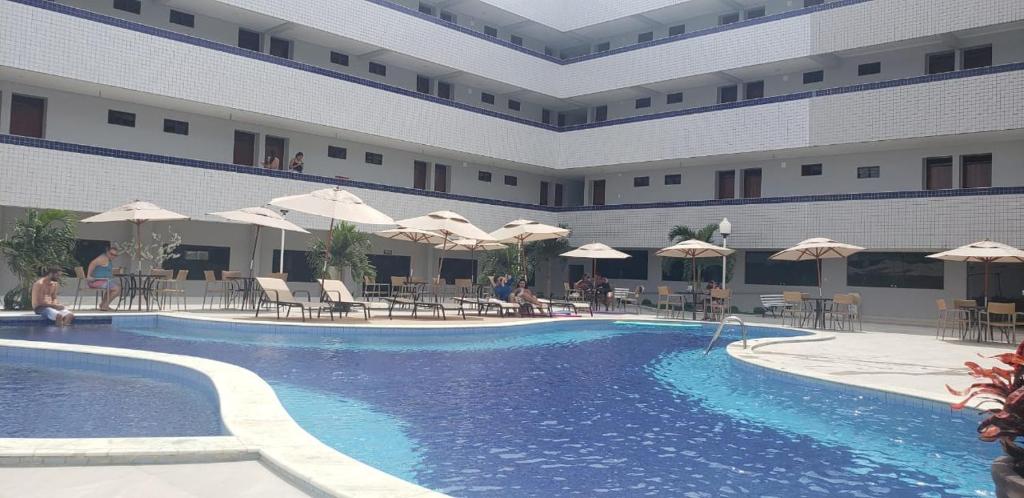 Belo JardimHotel Asa Branca的一个带桌子和遮阳伞的酒店游泳池