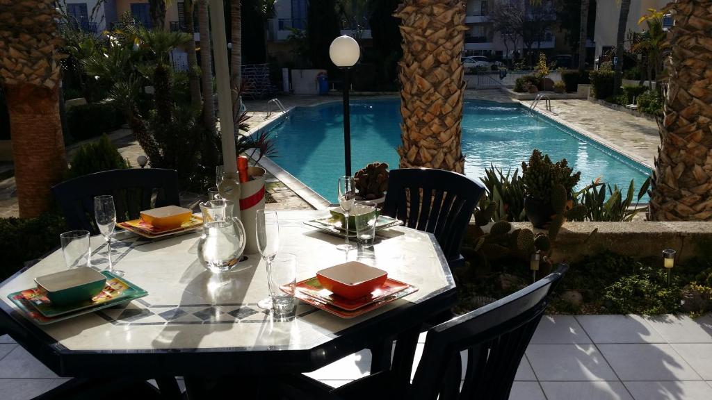 帕福斯Maya's Apartment - Complimentary Paphos Airport Transport的一张桌子,上面有盘子,放在游泳池边