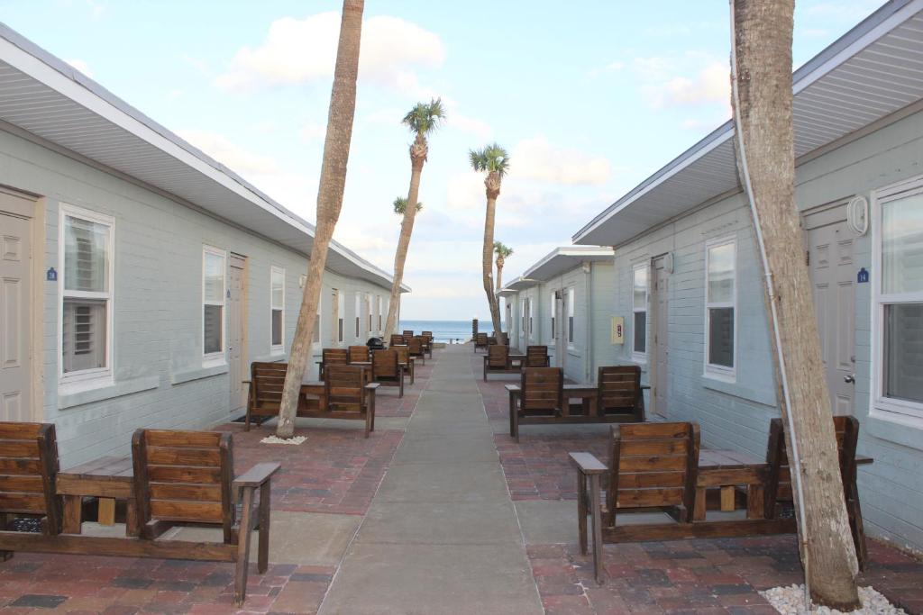 代托纳海滩Shoreline Suites & Cabana Cottages – Beachfront的一排房子,长椅和棕榈树