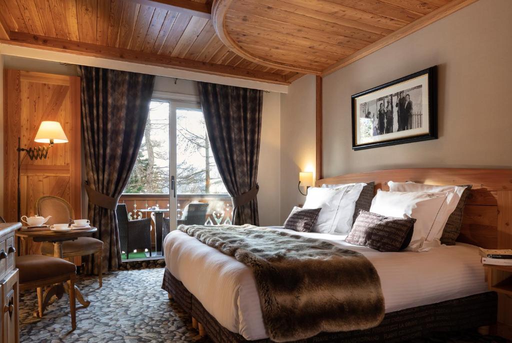 莱德萨阿尔卑斯Hôtel Chalet Mounier的酒店客房设有一张大床和一张桌子。