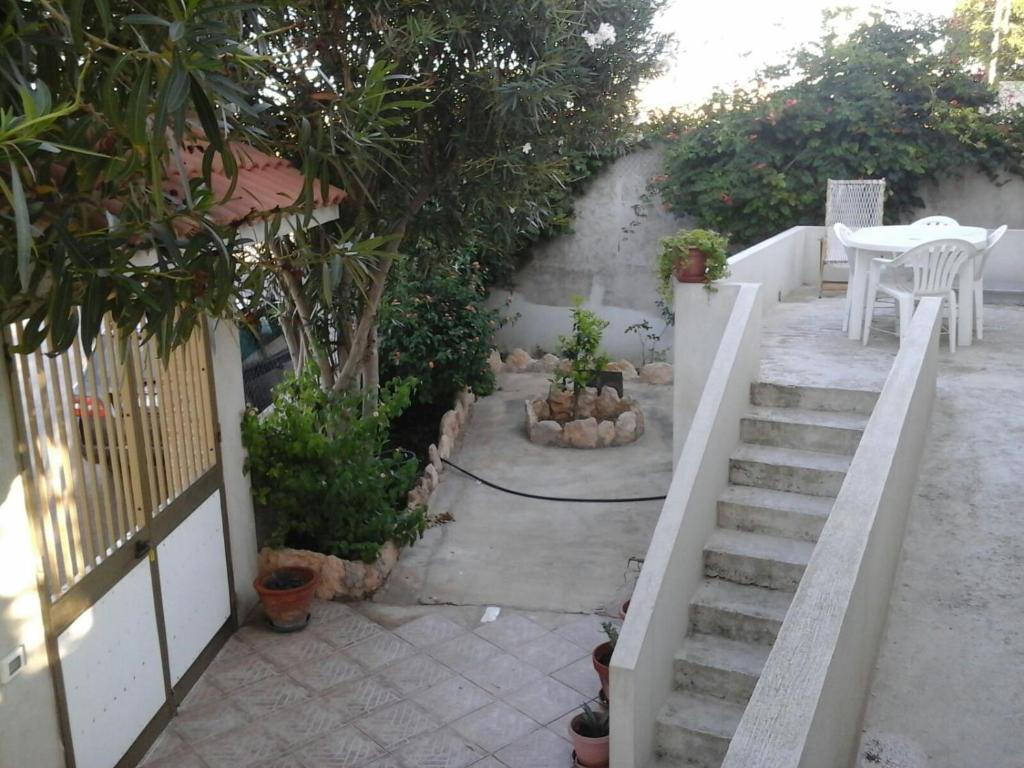 兰佩杜萨Appartamento con giardino的庭院设有楼梯、桌子和树木