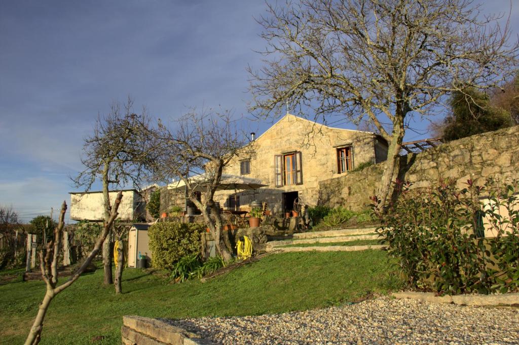 蒙达里斯Vinosobroso Casa Rural的石头房子,有石墙和树木
