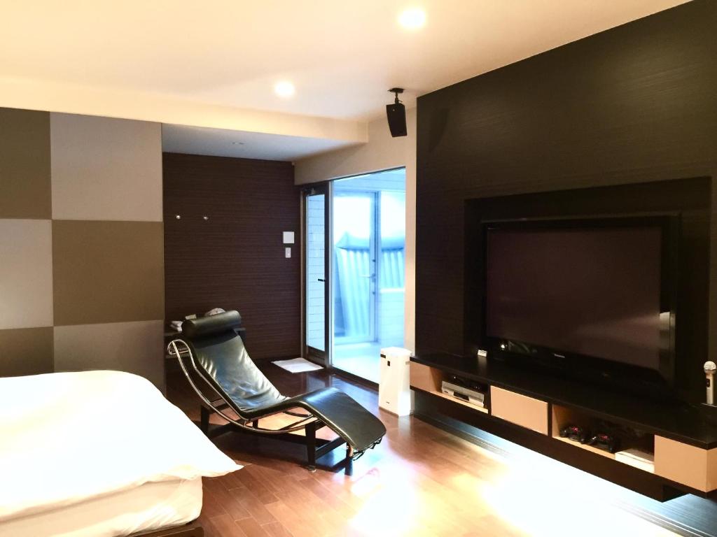 东广岛市LUXe的一间卧室配有电视、一张床和一把椅子