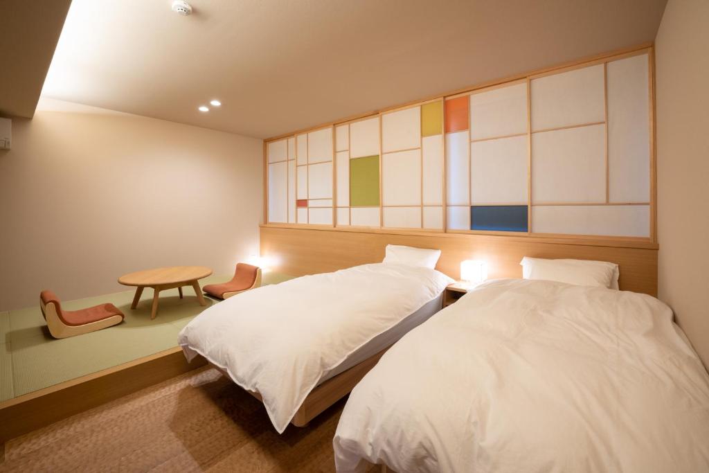 金泽marutto Ishikawa的一间卧室设有两张床、一张桌子和一个窗口