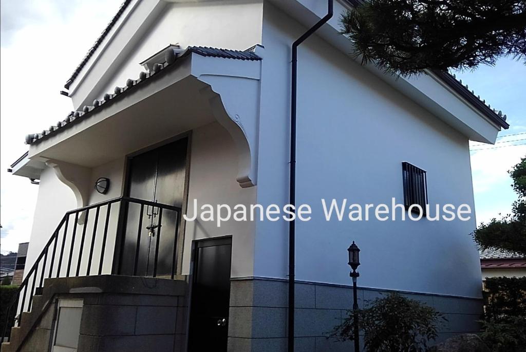 新宫市くまの蔵inn Warehouse的一间白色的房子,上面有看日本仓库的标志
