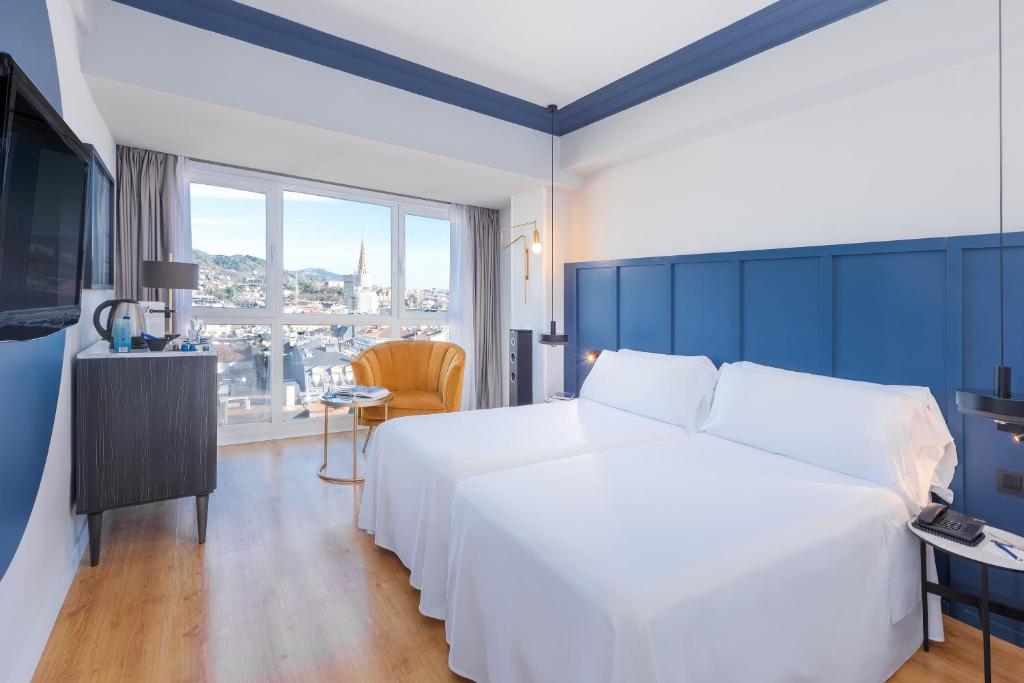 圣塞瓦斯蒂安Hotel San Sebastián Orly, Affiliated by Meliá的酒店客房设有白色的床和大窗户。