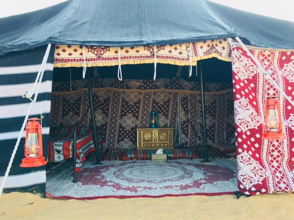BadīyahSultan Private Desert Camp的帐篷里设有桌子和宝座