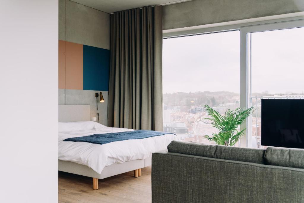 鲁汶De Hoorn的一间卧室配有一张床、一张沙发和一个大窗户