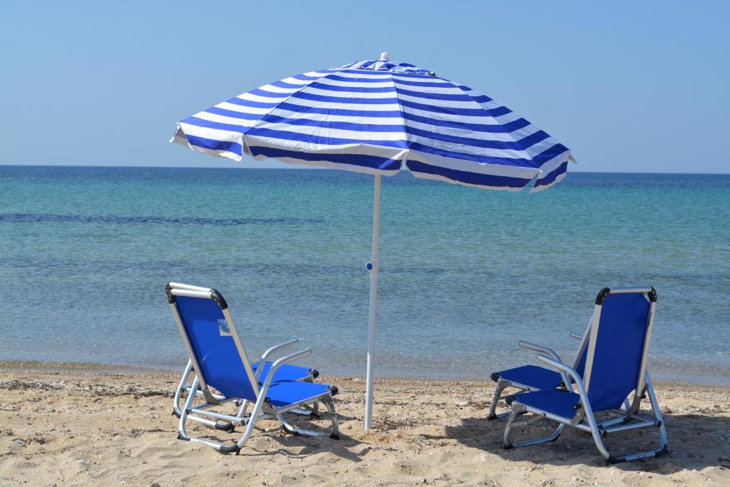 帕拉利亚狄奥尼索Zoi Apartments的海滩上的两把椅子和一把遮阳伞