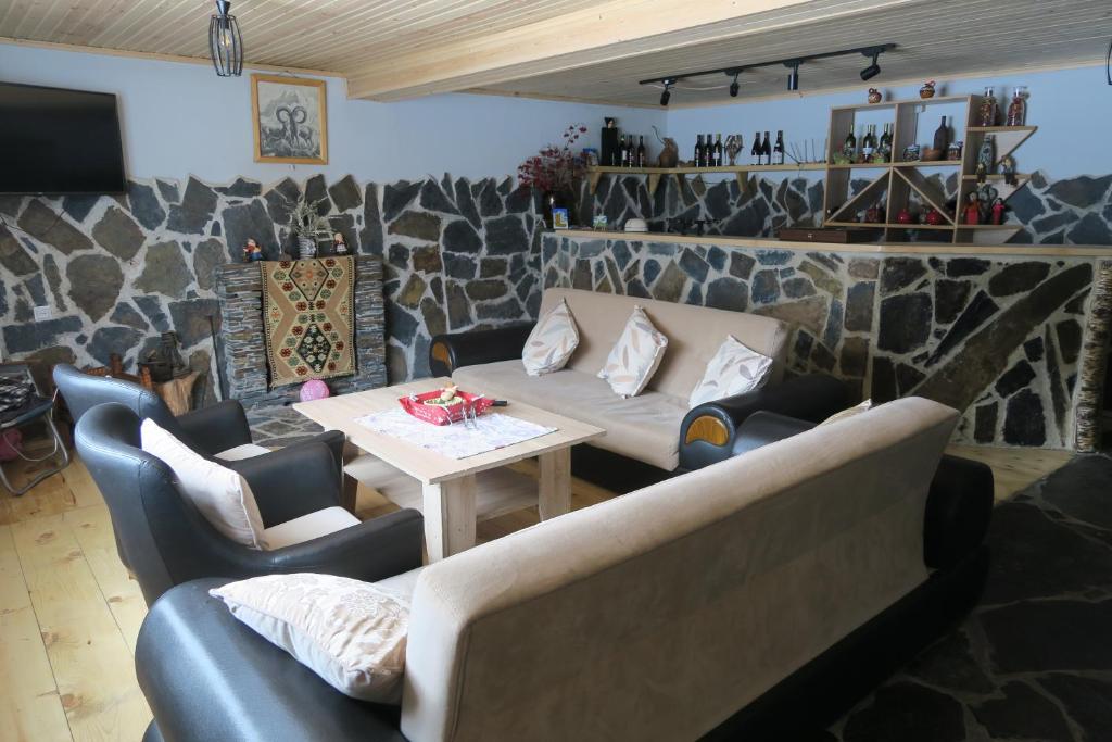 梅斯蒂亚Guest House Lashmina的带沙发、桌子和石墙的客厅
