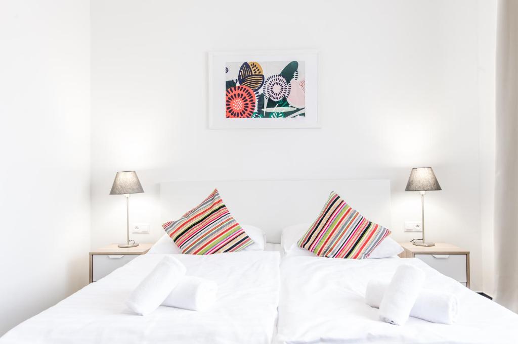 布拉迪斯拉发佩蒂特迪潘登思旅馆的一间白色卧室,配有两张床和两盏灯。