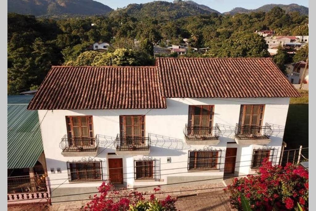 科潘玛雅遗址La Casa de Dona Irma Townhouse的白色的房子,设有窗户和屋顶