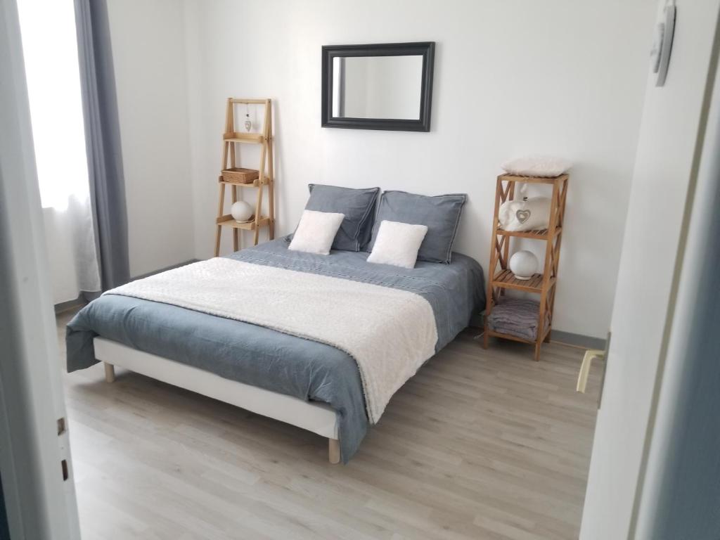 圣达穆尔GITE LE SAINT-AMOUR的一间卧室配有一张带蓝色床单和镜子的床